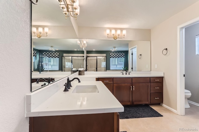 bathroom featuring a chandelier, a shower stall, tile patterned flooring, vanity, and toilet