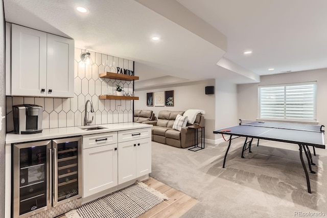 indoor wet bar featuring beverage cooler, recessed lighting, decorative backsplash, light wood-style flooring, and baseboards