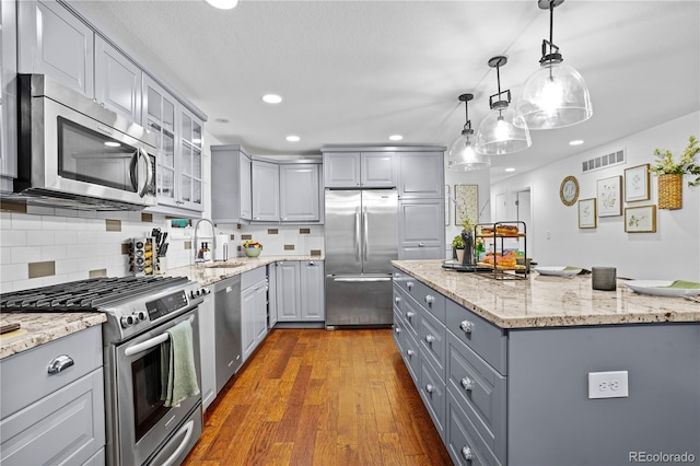 kitchen with appliances with stainless steel finishes, tasteful backsplash, gray cabinets, and sink