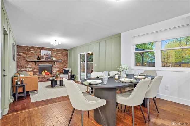 dining space with dark hardwood / wood-style flooring, a brick fireplace, and a wealth of natural light