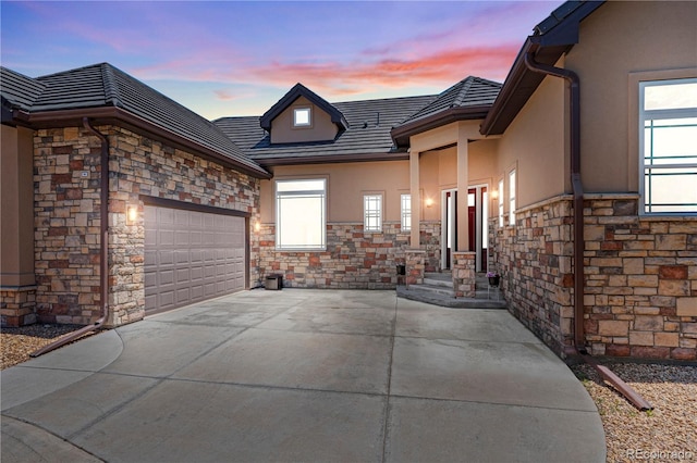 6532 S Tempe St, Aurora, CO 80016 - view of front facade with stone siding, an attached garage, stucco siding, and driveway