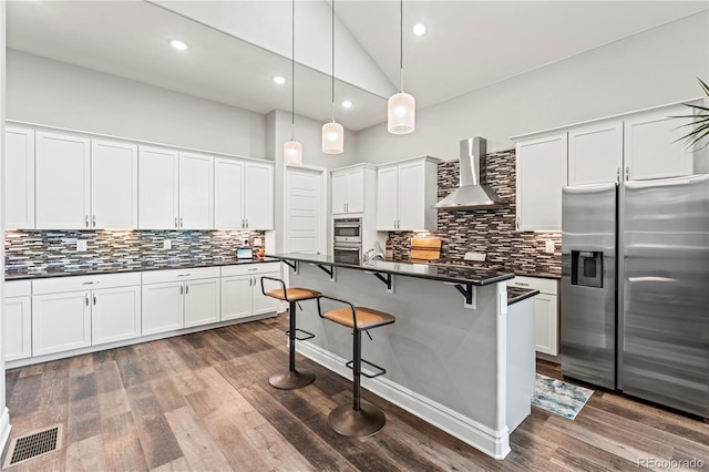 6532 S Tempe St, Aurora, CO 80016 - kitchen with stainless steel appliances, wall chimney exhaust hood, dark countertops, high vaulted ceiling, and a kitchen breakfast bar
