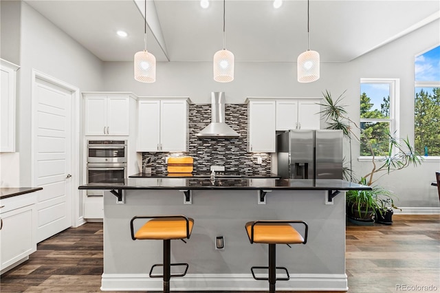 6532 S Tempe St, Aurora, CO 80016 - kitchen with wall chimney exhaust hood, stainless steel appliances, dark countertops, recessed lighting, and vaulted ceiling
