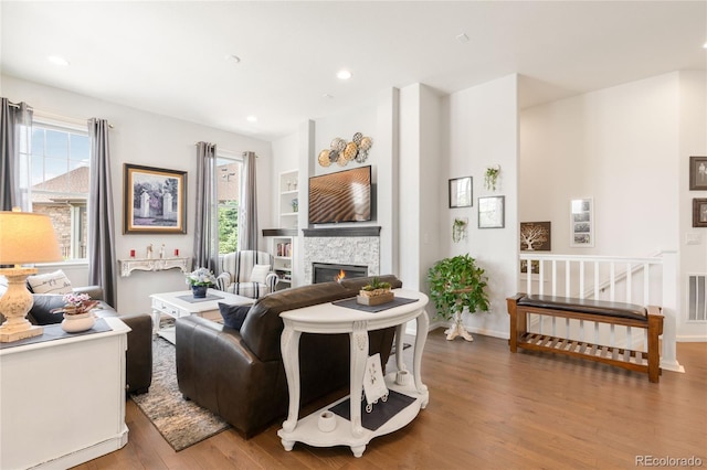 25049 E Alder Dr, Aurora, CO 80016 - living area featuring healthy amount of natural light, wood finished floors, a glass covered fireplace, recessed lighting, and baseboards