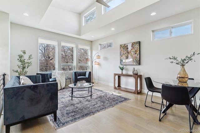 living room featuring a towering ceiling, light hardwood / wood-style flooring, and plenty of natural light