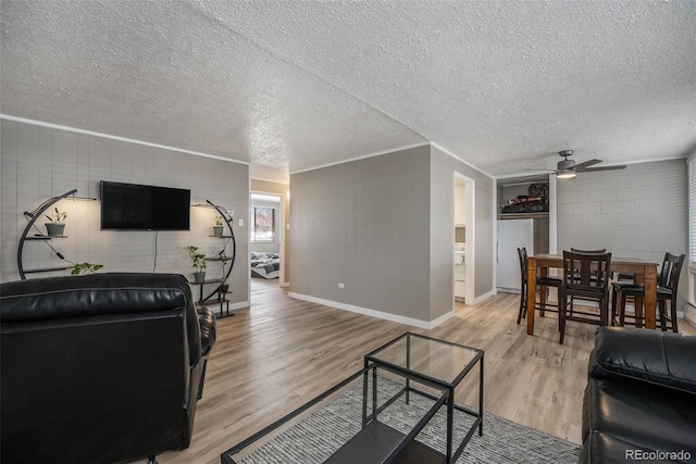 living room featuring light wood finished floors, baseboards, a textured ceiling, and a ceiling fan