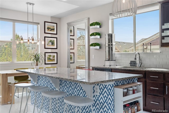 198 Calhoun Cir, Castle Rock, CO 80104 - kitchen featuring a sink, tasteful backsplash, open shelves, light stone counters, and an inviting chandelier