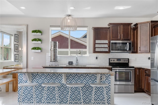 198 Calhoun Cir, Castle Rock, CO 80104 - kitchen with dark brown cabinets, light stone countertops, appliances with stainless steel finishes, and decorative backsplash