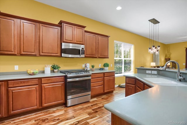 3419 Traver Dr, Broomfield, CO 80023 - kitchen with light countertops, stainless steel appliances, hanging light fixtures, a sink, and light wood-style flooring