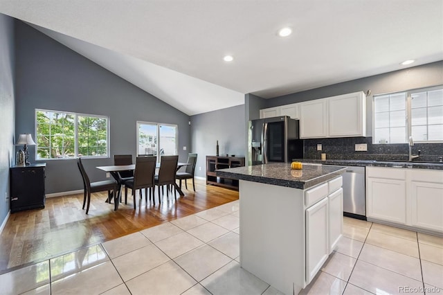 5229 Nighthawk Pkwy, Brighton, CO 80601 - kitchen featuring refrigerator with ice dispenser, dishwasher, a kitchen island, white cabinets, and vaulted ceiling