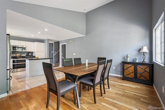 5229 Nighthawk Pkwy, Brighton, CO 80601 - dining space with light wood-style flooring, a towering ceiling, stairs, and recessed lighting