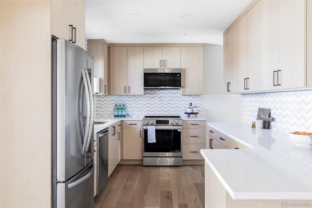 kitchen featuring light countertops, appliances with stainless steel finishes, light wood-style floors, light brown cabinets, and a peninsula