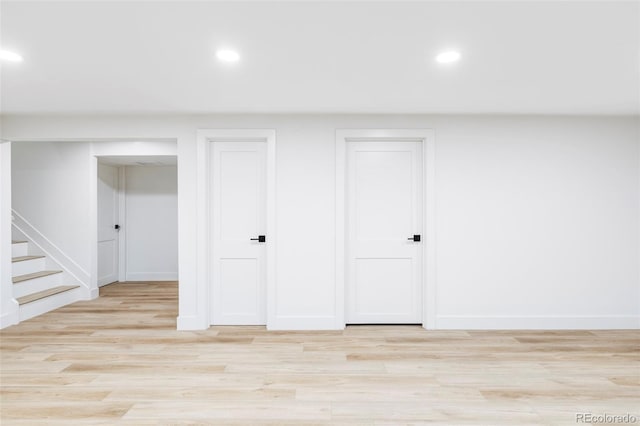 basement featuring baseboards, stairs, light wood-style flooring, and recessed lighting