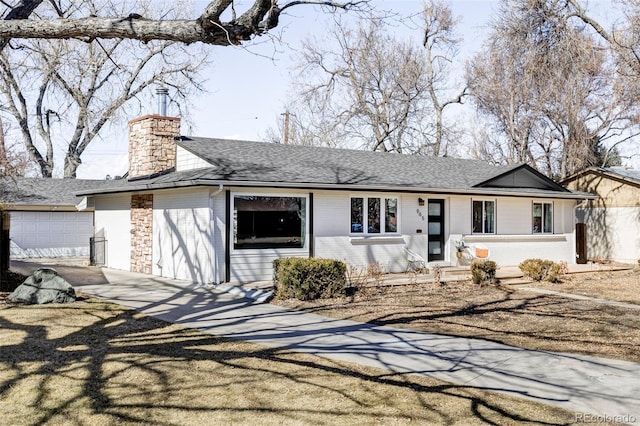 view of front of house with brick siding, a chimney, concrete driveway, and roof with shingles