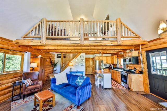 living room featuring hardwood / wood-style floors, high vaulted ceiling, sink, and log walls