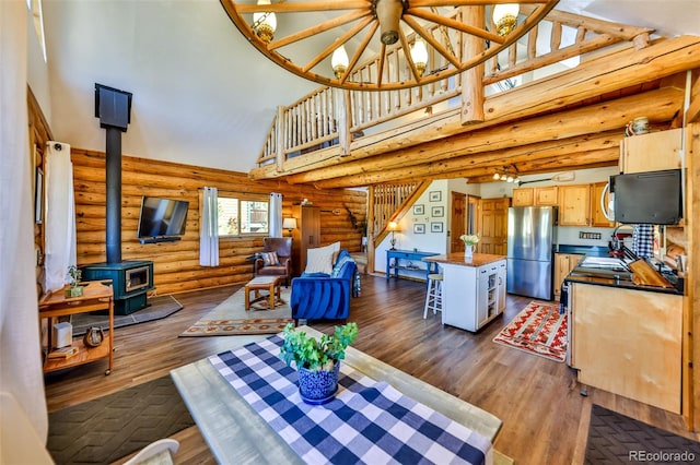 living room featuring a wood stove, high vaulted ceiling, rustic walls, and dark hardwood / wood-style flooring