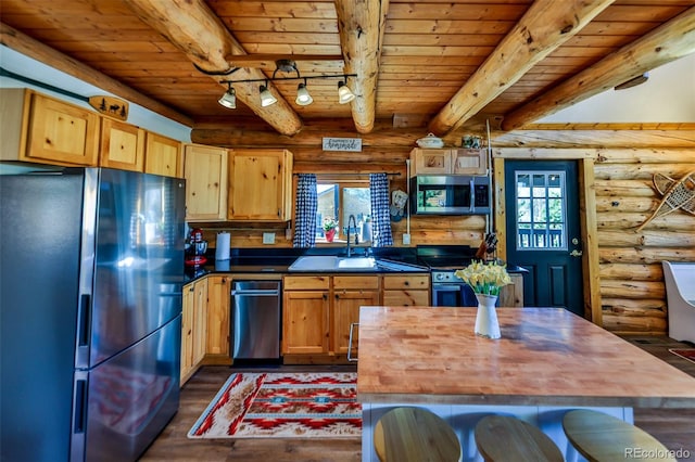 kitchen with appliances with stainless steel finishes, wood ceiling, wooden counters, and rustic walls