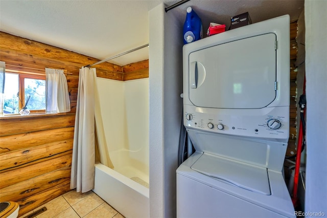 washroom featuring a textured ceiling, stacked washer / drying machine, light tile patterned flooring, and log walls