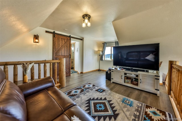 living room with dark hardwood / wood-style floors, a barn door, a textured ceiling, and vaulted ceiling