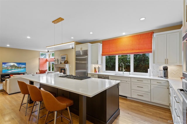 1479 S Clarkson St, Denver, CO 80210 - kitchen featuring appliances with stainless steel finishes, white cabinetry, open floor plan, backsplash, and recessed lighting