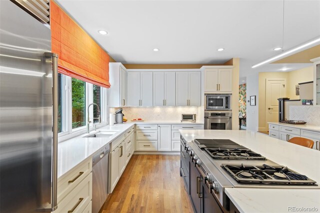 1479 S Clarkson St, Denver, CO 80210 - kitchen with stainless steel appliances, white cabinetry, backsplash, light wood-style flooring, and recessed lighting