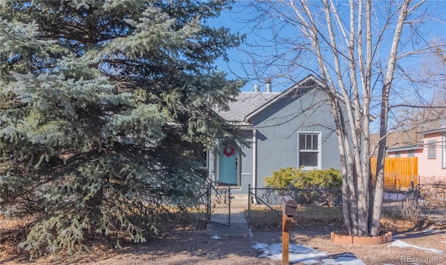 view of front of house with a fenced front yard, a gate, a shingled roof, and stucco siding