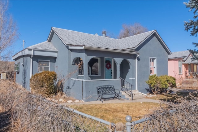 view of front of property with a porch, roof with shingles, and stucco siding