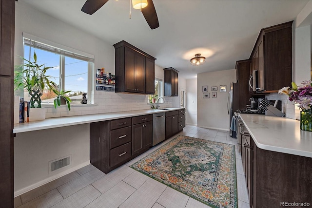 kitchen featuring appliances with stainless steel finishes, ceiling fan, light tile patterned floors, dark brown cabinets, and decorative backsplash