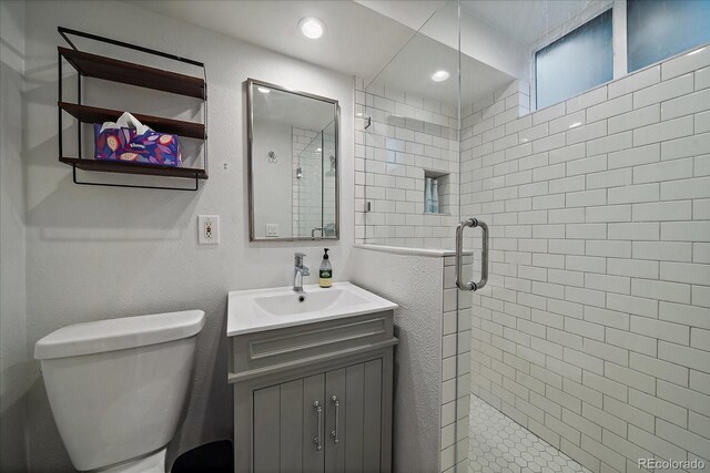 bathroom with walk in shower, vanity, and toilet