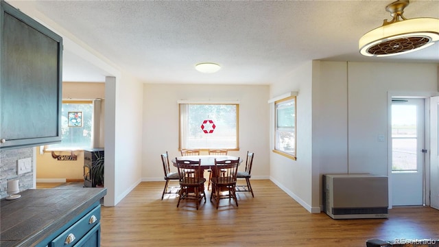 dining space with light hardwood / wood-style floors, a textured ceiling, and a wealth of natural light