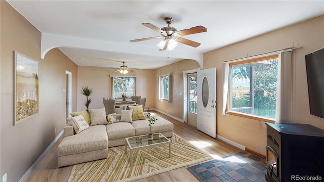 living room with hardwood / wood-style floors, a wood stove, and ceiling fan