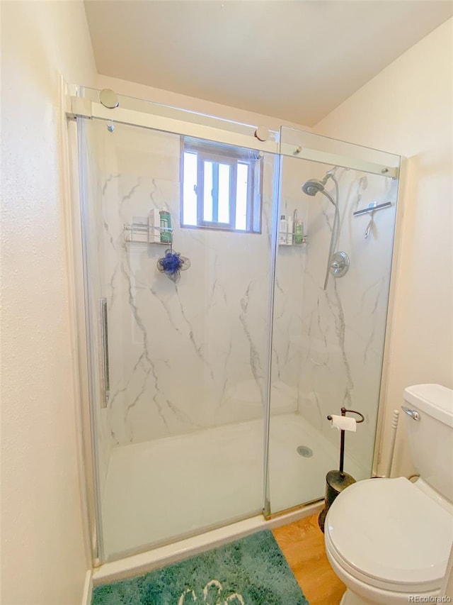 bathroom with a shower with door, hardwood / wood-style floors, and toilet