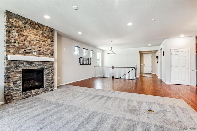 unfurnished living room featuring carpet flooring, a textured ceiling, and a stone fireplace