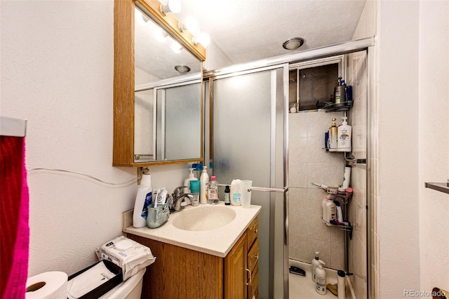 bathroom featuring vanity, toilet, a shower with shower door, and a textured ceiling