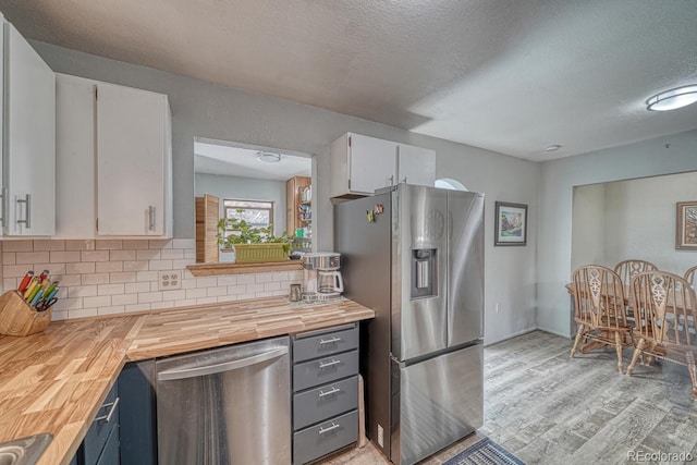 114 Loop Dr, Howard, CO 81233 - kitchen with appliances with stainless steel finishes, wood counters, tasteful backsplash, light wood-type flooring, and white cabinets