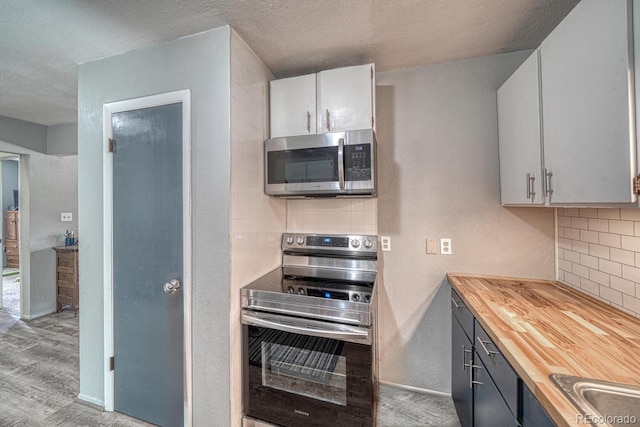 114 Loop Dr, Howard, CO 81233 - kitchen with appliances with stainless steel finishes, wooden counters, light wood-type flooring, tasteful backsplash, and a textured ceiling