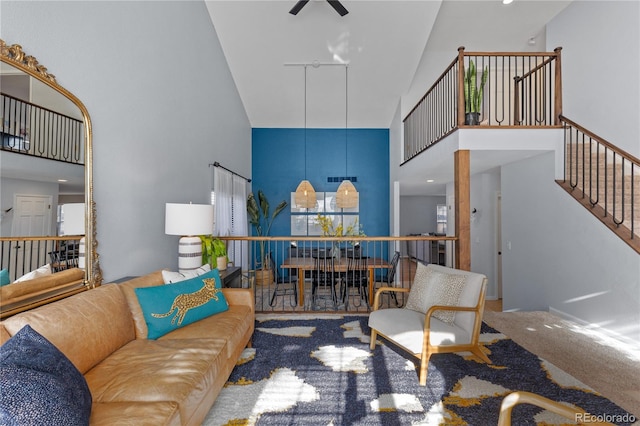 carpeted living area with stairway, a towering ceiling, and ceiling fan