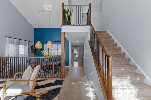 entryway with stairway, baseboards, a high ceiling, and visible vents