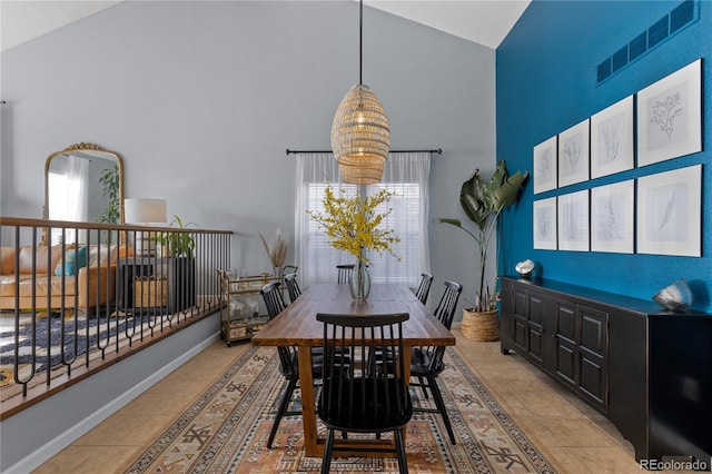 dining room with light tile patterned floors, visible vents, high vaulted ceiling, and baseboards