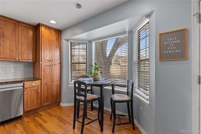 kitchen with backsplash, baseboards, dishwasher, brown cabinets, and light wood-style flooring