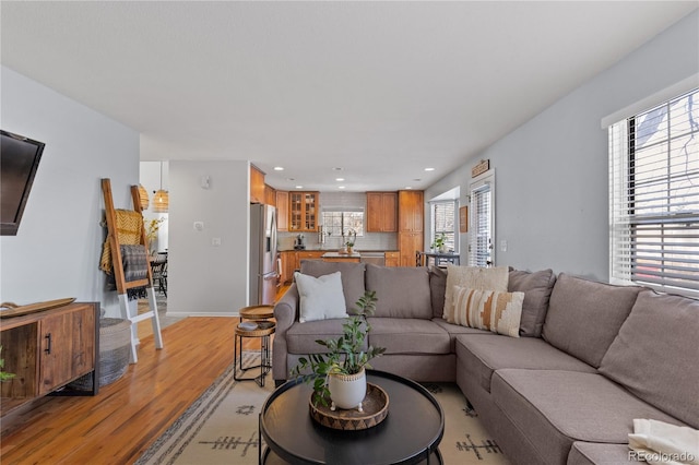 living room with light wood finished floors, recessed lighting, and baseboards