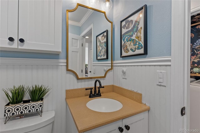 half bath with toilet, ornamental molding, washer / clothes dryer, wainscoting, and vanity