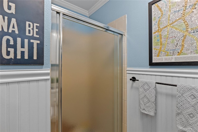 full bathroom featuring a wainscoted wall, a stall shower, and crown molding