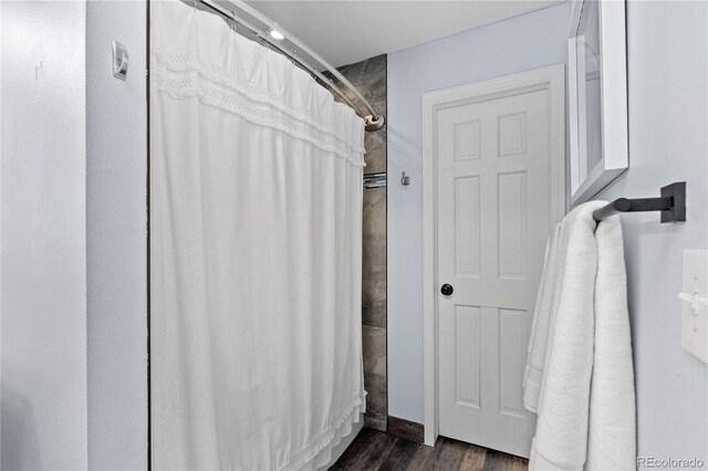 bathroom with curtained shower and wood finished floors