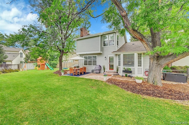 back of house with a playground, a lawn, a chimney, a fenced backyard, and a patio