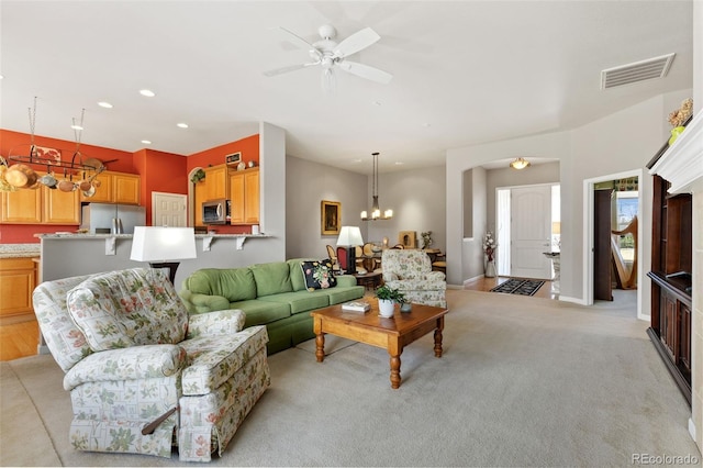 living room featuring recessed lighting, ceiling fan with notable chandelier, light carpet, visible vents, and baseboards