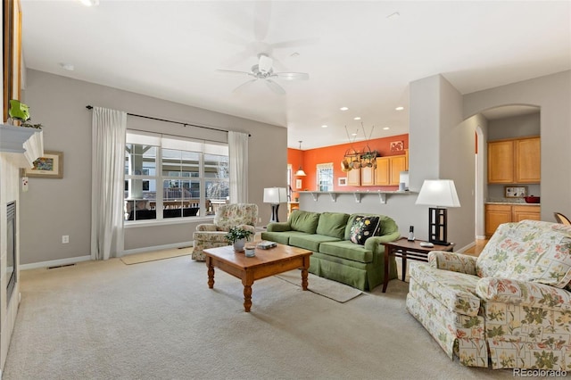 living area with light colored carpet, a fireplace, a ceiling fan, baseboards, and visible vents