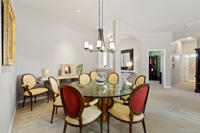 dining space with baseboards, visible vents, arched walkways, light colored carpet, and a chandelier