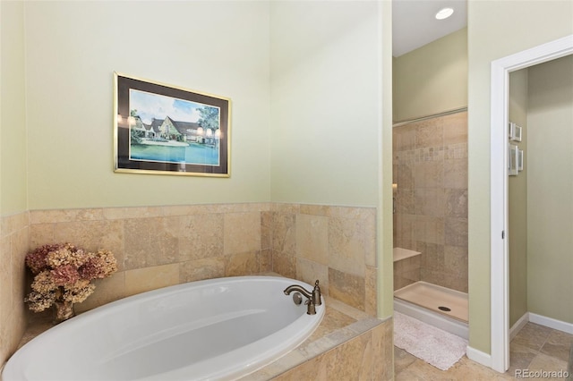 full bath with tile patterned flooring, a tile shower, a bath, and baseboards