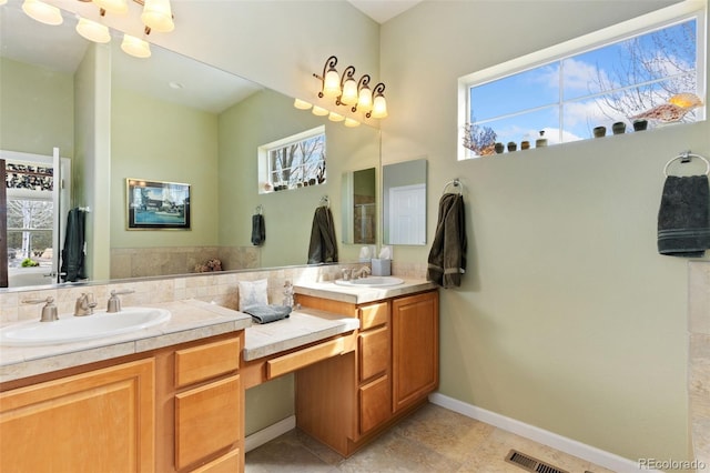 bathroom with double vanity, baseboards, visible vents, and a sink